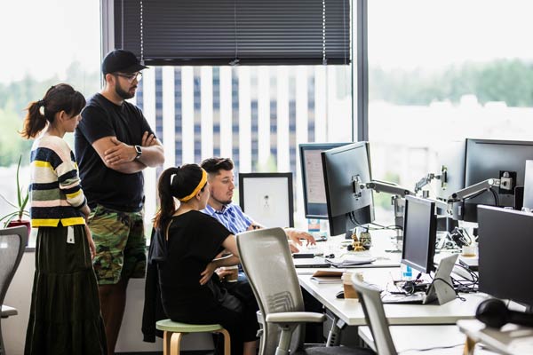 four people gathered around a desk looking at a computer