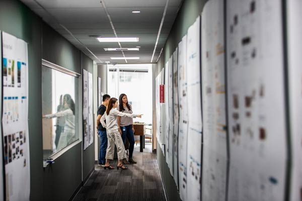 three people in a hallway pointing at something out of frame